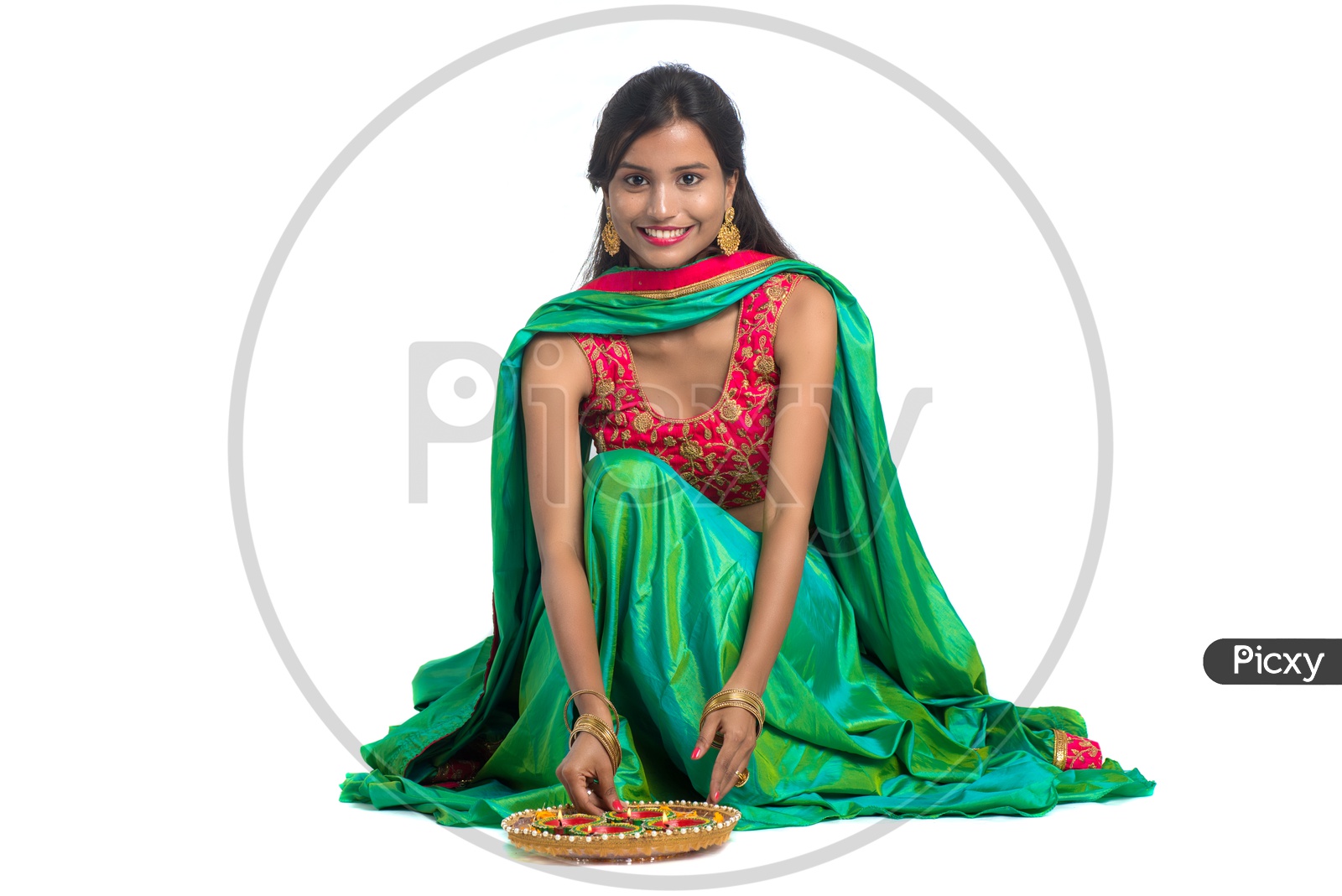Portrait Of a Young Traditional Indian Woman Holding Festival Dia and Making Rangoli  in Hand over a White Isolated Background