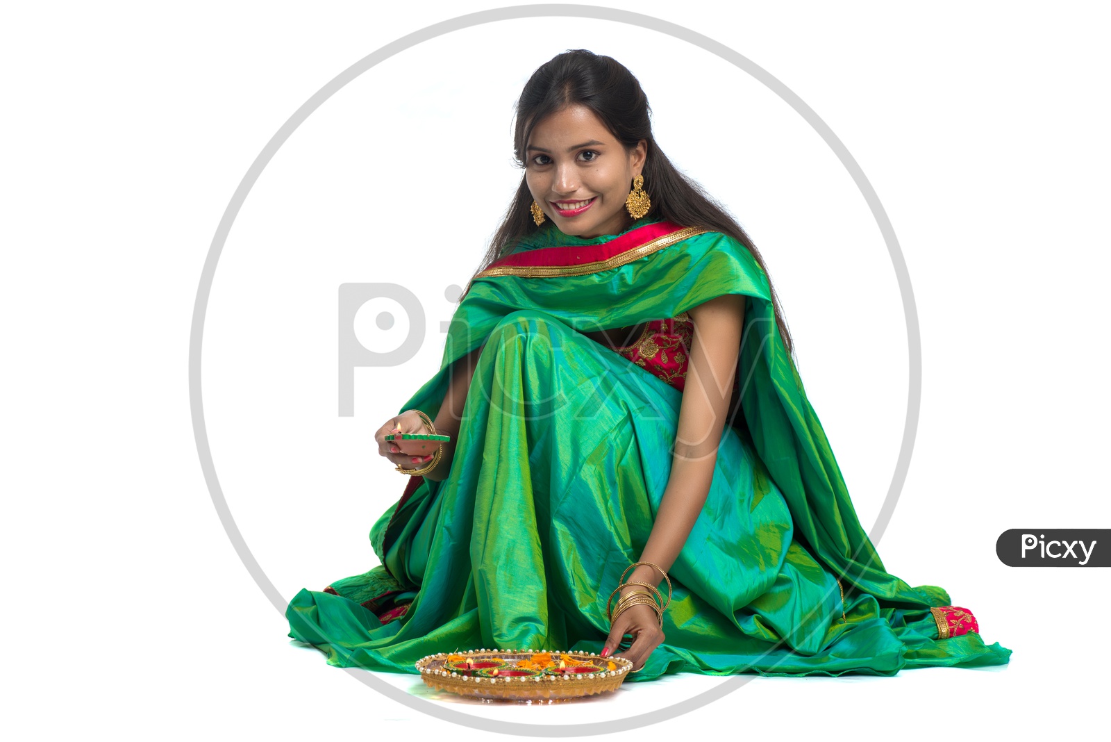 Portrait Of a Young Traditional Indian Woman Holding Festival Dia and Making Rangoli  in Hand over a White Isolated Background