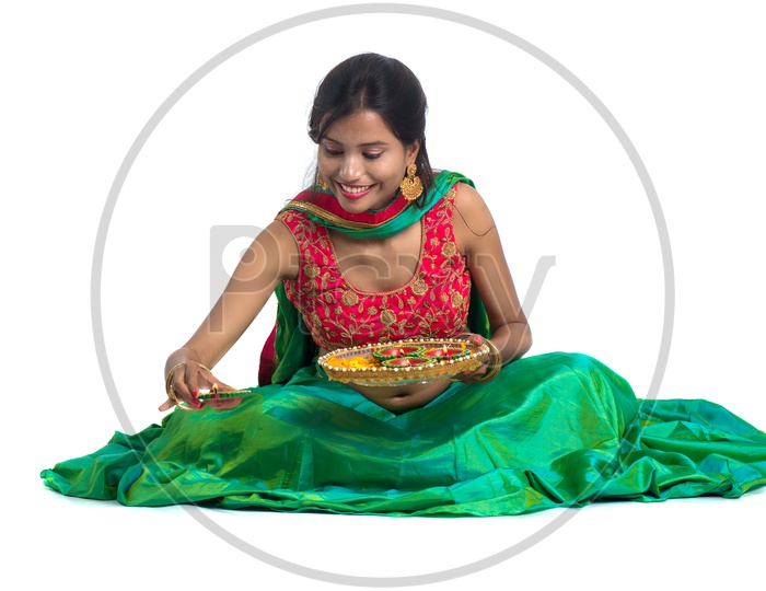 Portrait of a Young Traditional Indian Girl With Festival Dia And  Making Rangoli  Over a Isolated white Background