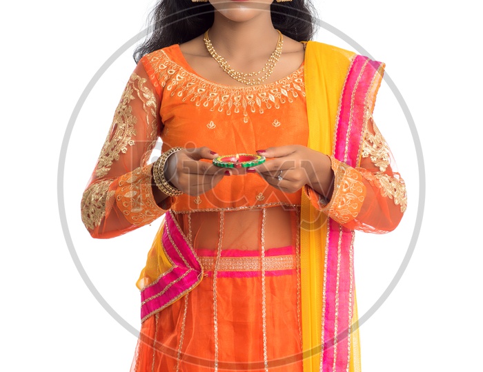 A young traditional smiling pretty Indian woman holding diyas in hand