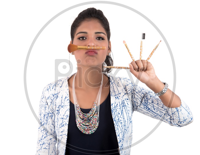 Young beautiful Girl Enjoying With Makeup Brushes On an Isolated White Background
