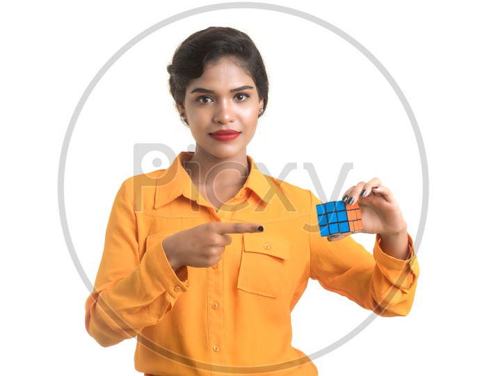Young Beautiful Girl With a Smile  Expression On Her Face and Holding Rubik's cube in hand on an isolated White Background