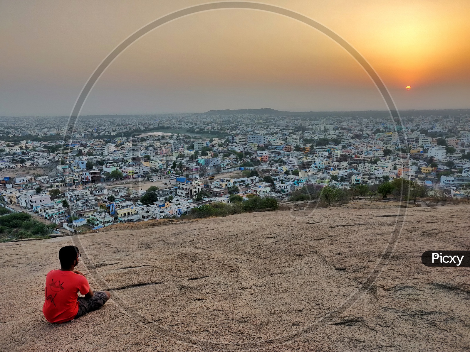 A Man Sitting On a Hill top And Enjoying The Hyderabad City Scape View