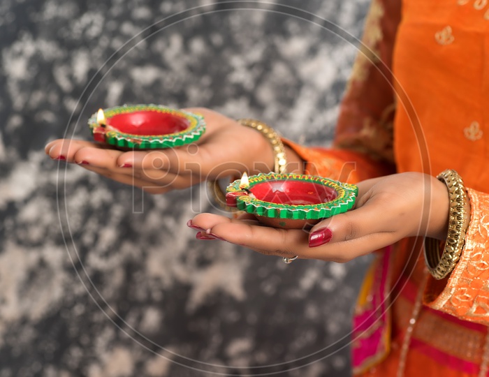 A young traditional Indian woman holding diyas in hand