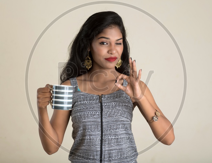Indian woman holding a mug making a super sign