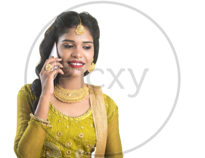 Young Traditional Indian Girl Speaking In Mobile phone Or Smart Phone With Smile On Her Face On an Isolated White Background