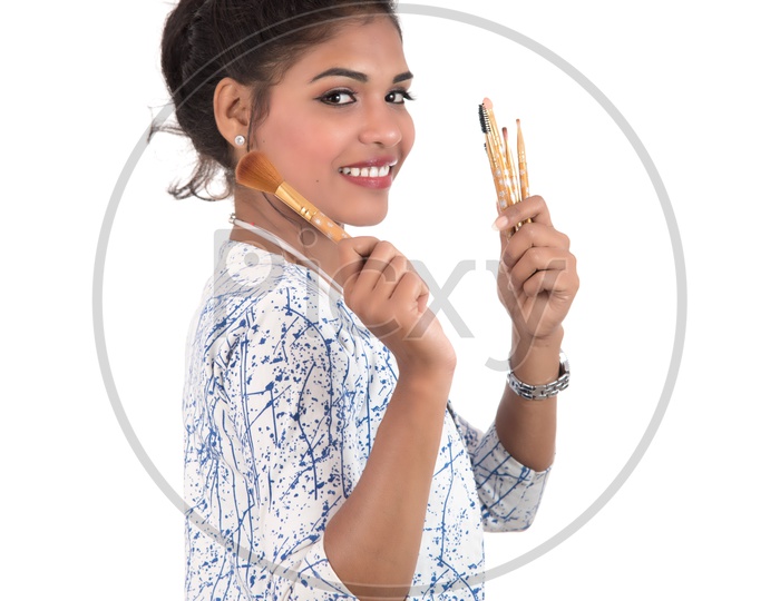 Young beautiful Girl Enjoying With Makeup Brushes On an Isolated White Background