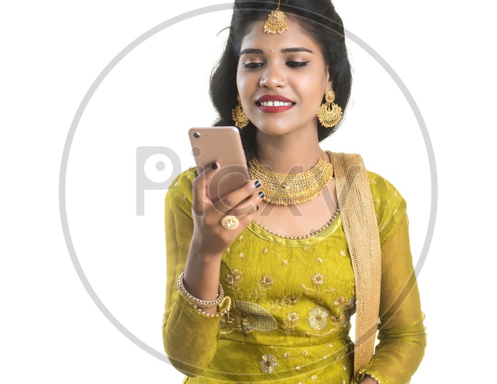 Young Traditional Indian Girl Using  Mobile phone Or Smart Phone With Smile On Her Face On an Isolated White Background