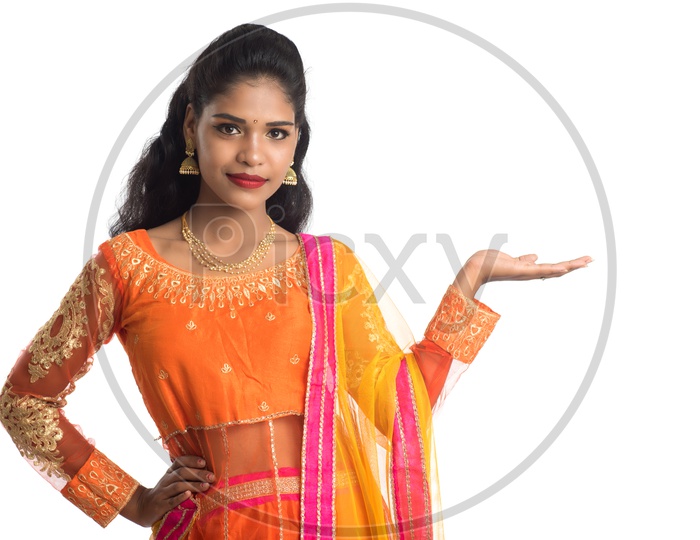A Young traditional Indian Woman Holding Something In Hand with an Expression  and Posing On an Isolated White Background