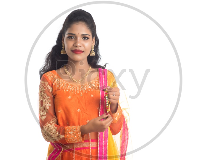 A Traditional Young Indian Girl Holding an Elegant Rakhi on Her a Hand On an Isolated White Background