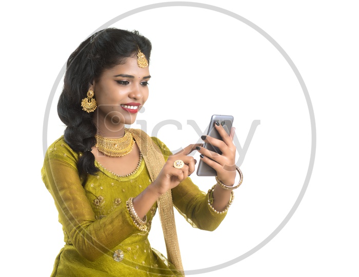 Young Traditional Indian Girl  Using  Mobile phone Or Smart Phone With Smile On Her Face On an Isolated White Background
