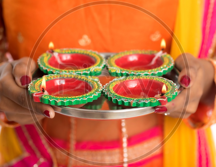 An Indian woman holding diyas in hand