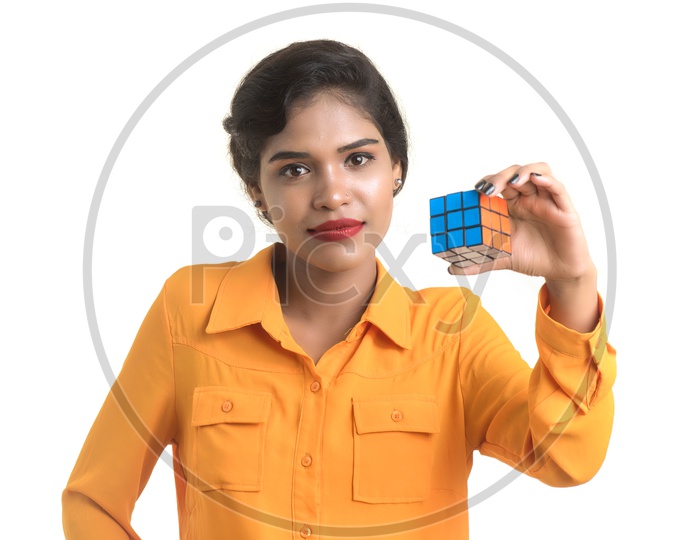 Indian woman wearing orange shirt holding a Rubik's cube