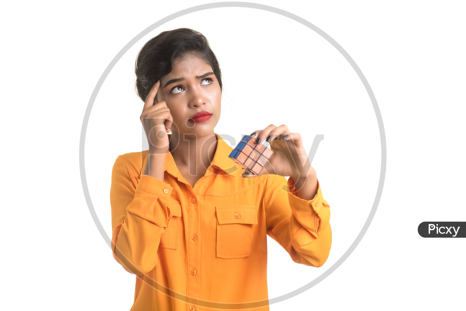 Indian woman wearing orange shirt holding a Rubik's Cube