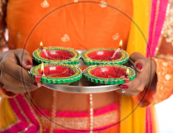 A young traditional Indian woman holding diyas in hand
