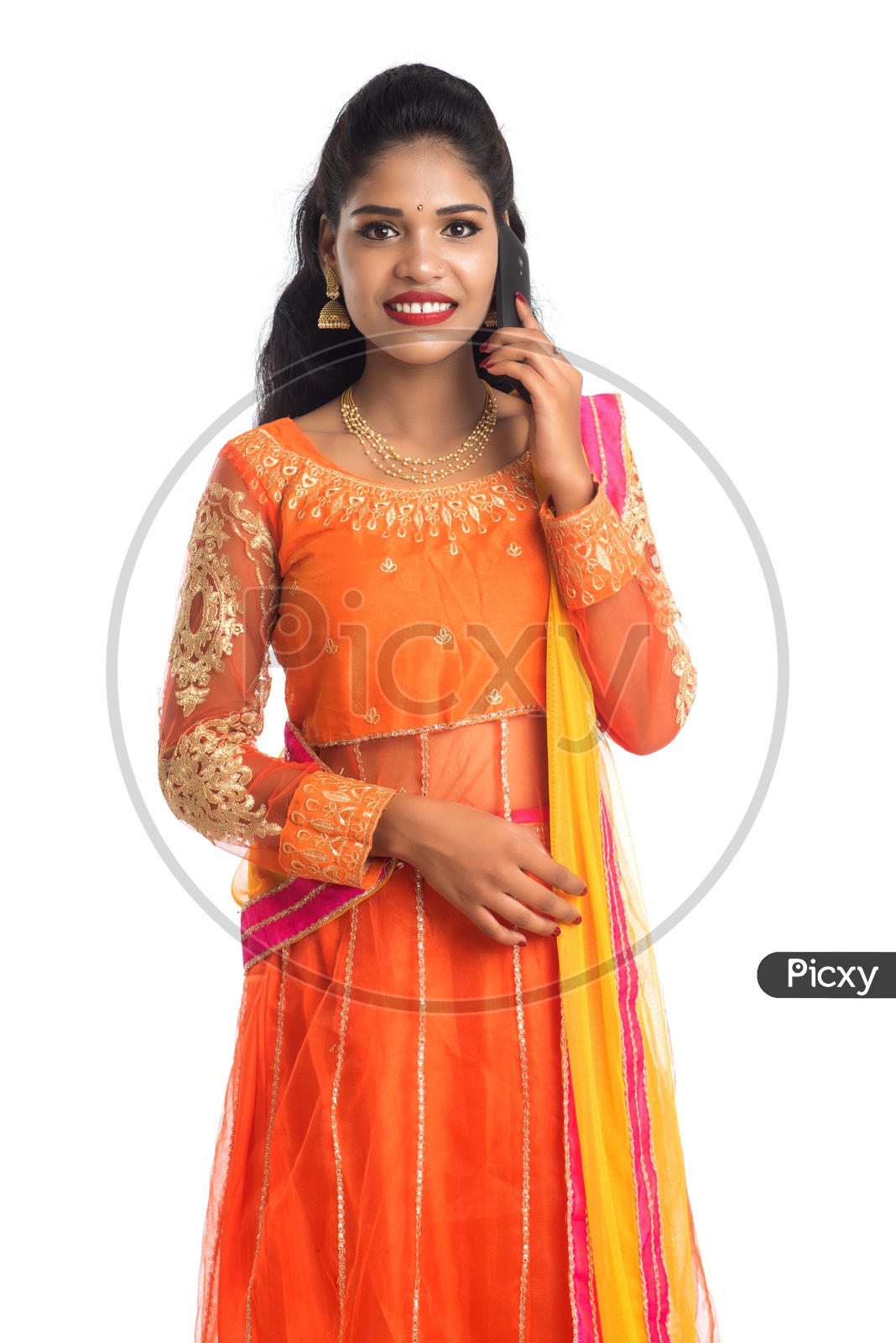 A young smiling Indian woman talking on a mobile phone or smart phone