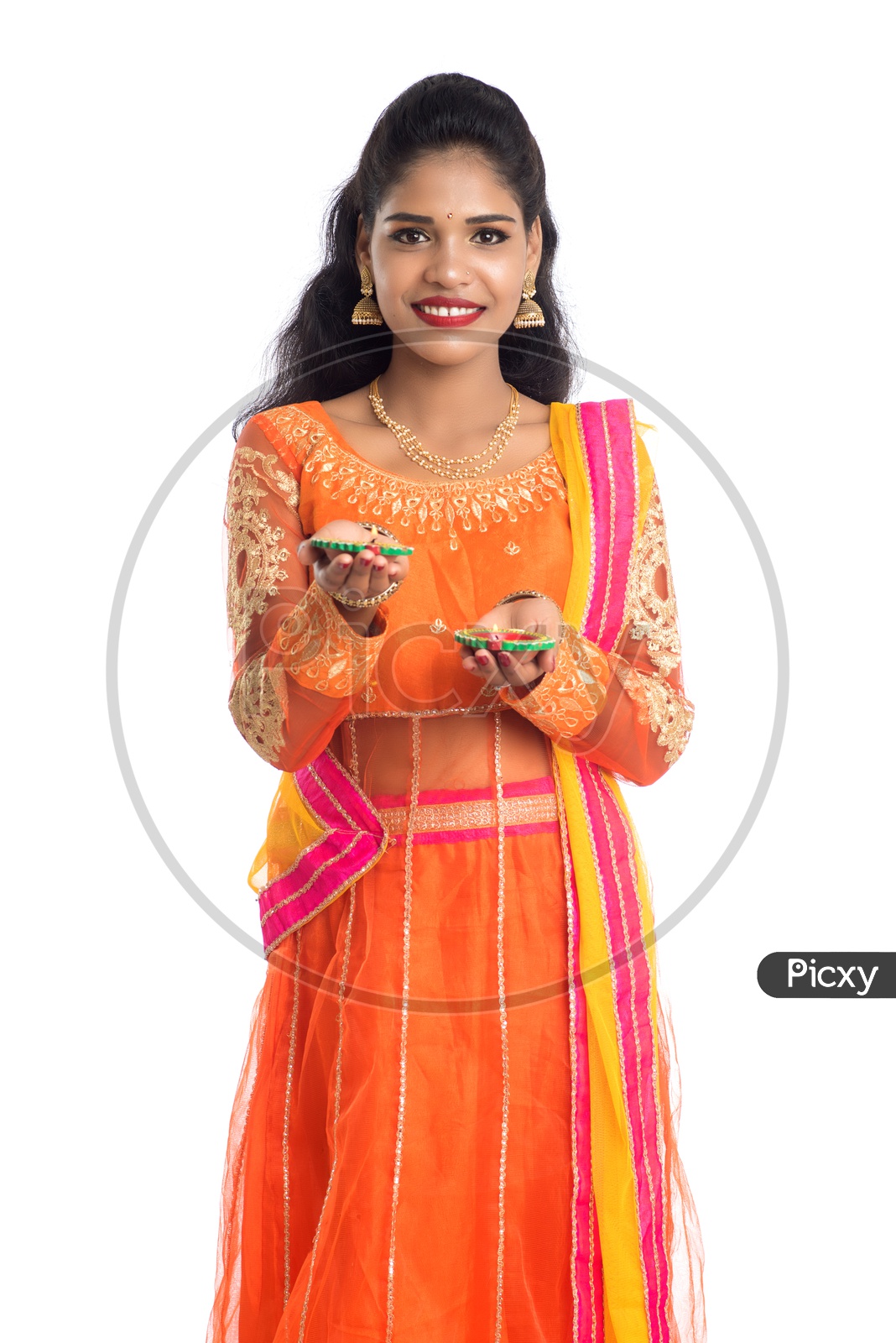 A young traditional smiling pretty Indian woman holding diyas in hand