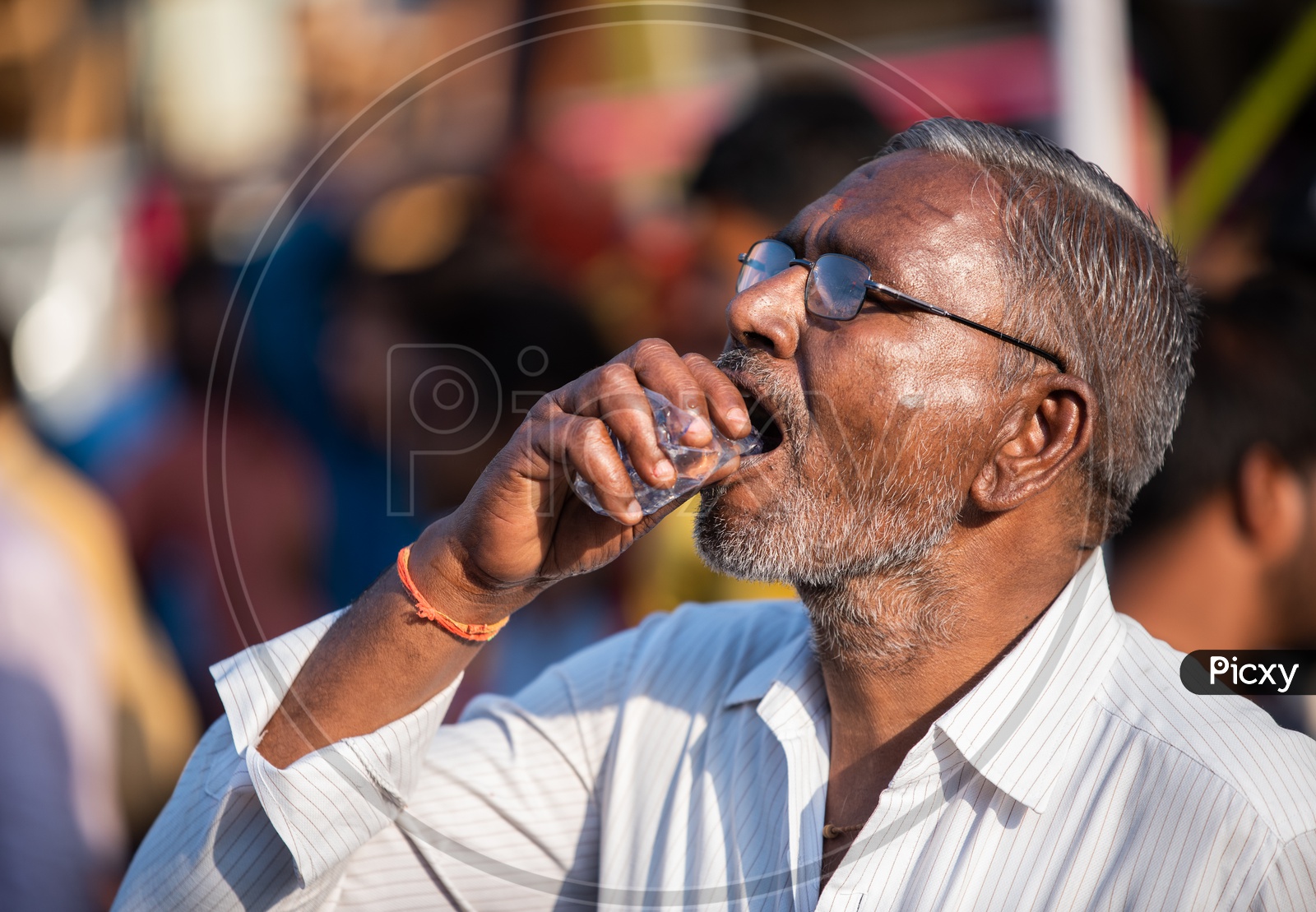 A man consuming plastic packaged drinking water on a hot summer day