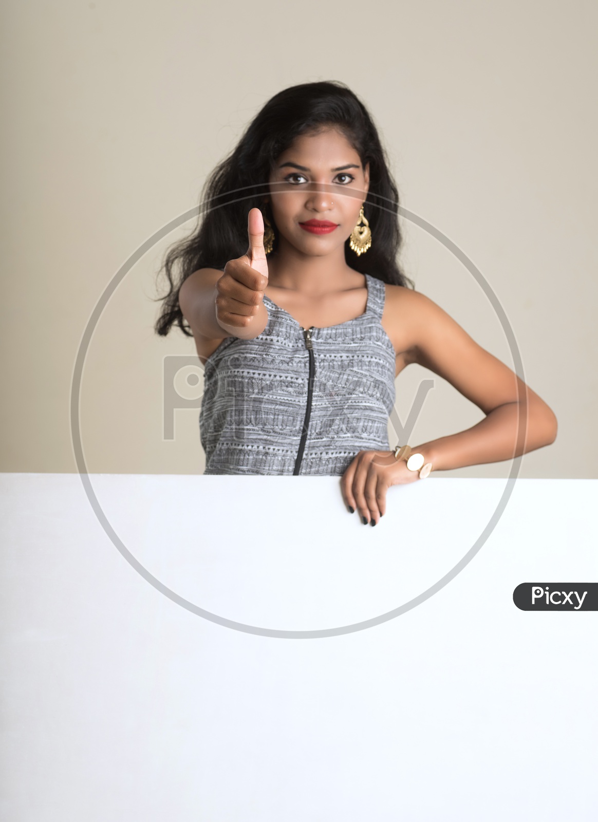 Indian woman holding a white board making a thumbs up sign