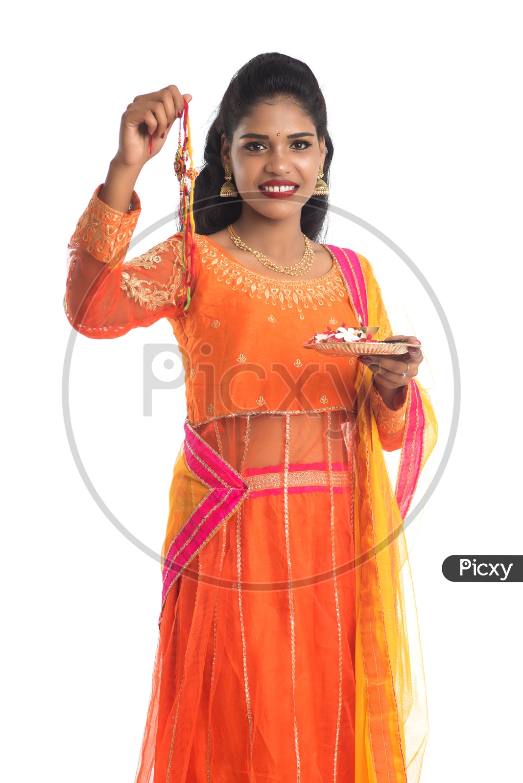 Young Indian Girl Holding Pooja Thali or Pooja Plate Along With an Elegant Rakhi For Her Brother  With a Smile Face on an Isolated White Background