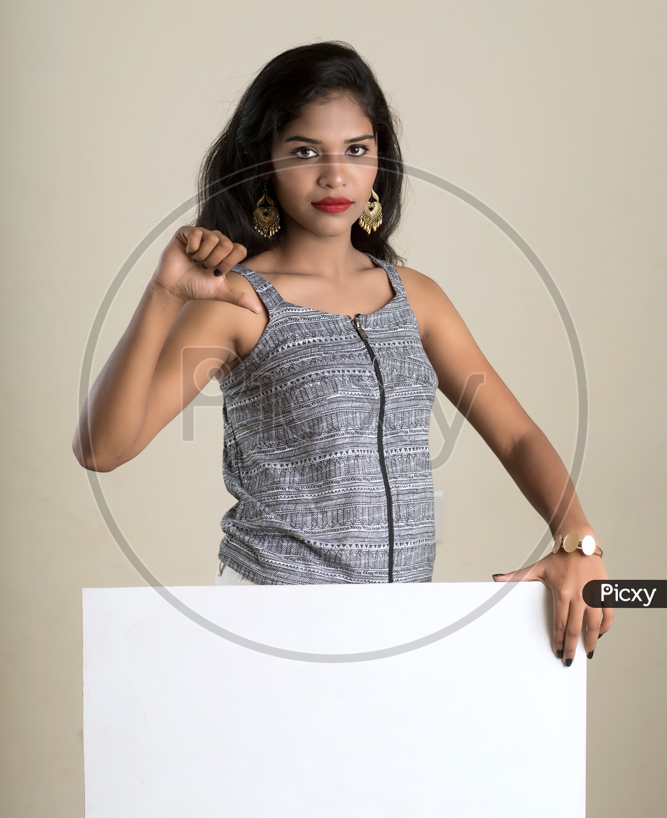 Indian woman holding a white board making a thumbs down sign