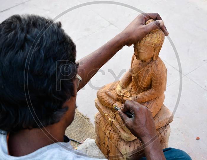 An Artist  Crafting Of Buddha Statue With Wood
