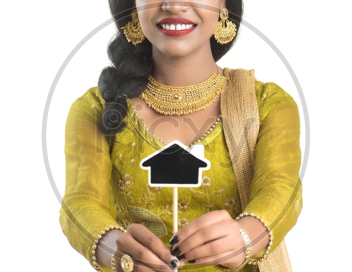 Happy Traditional Woman Holding A Little House Cutout Board in Her hand on an Isolated White Background