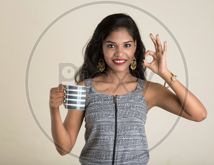Indian woman holding a mug making a super sign