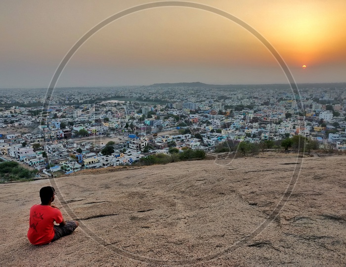 A Man Sitting On a Hill top And Enjoying The Hyderabad City Scape View