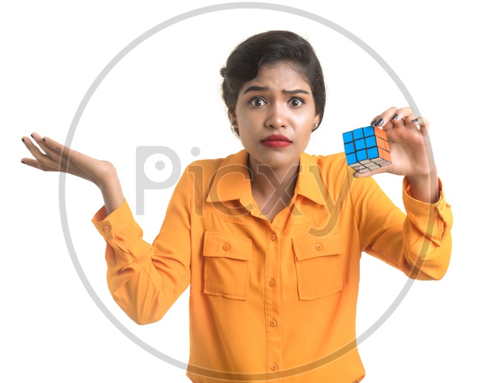 Young Beautiful Girl With a Puzzled Expression On Her Face and Holding Rubik's cube in hand on an isolated White Background