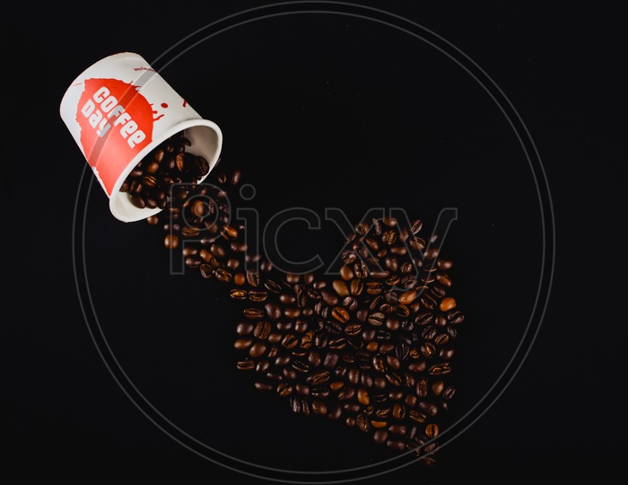 A Composition Shot Of Coffee Beans And Coffee Day Cup