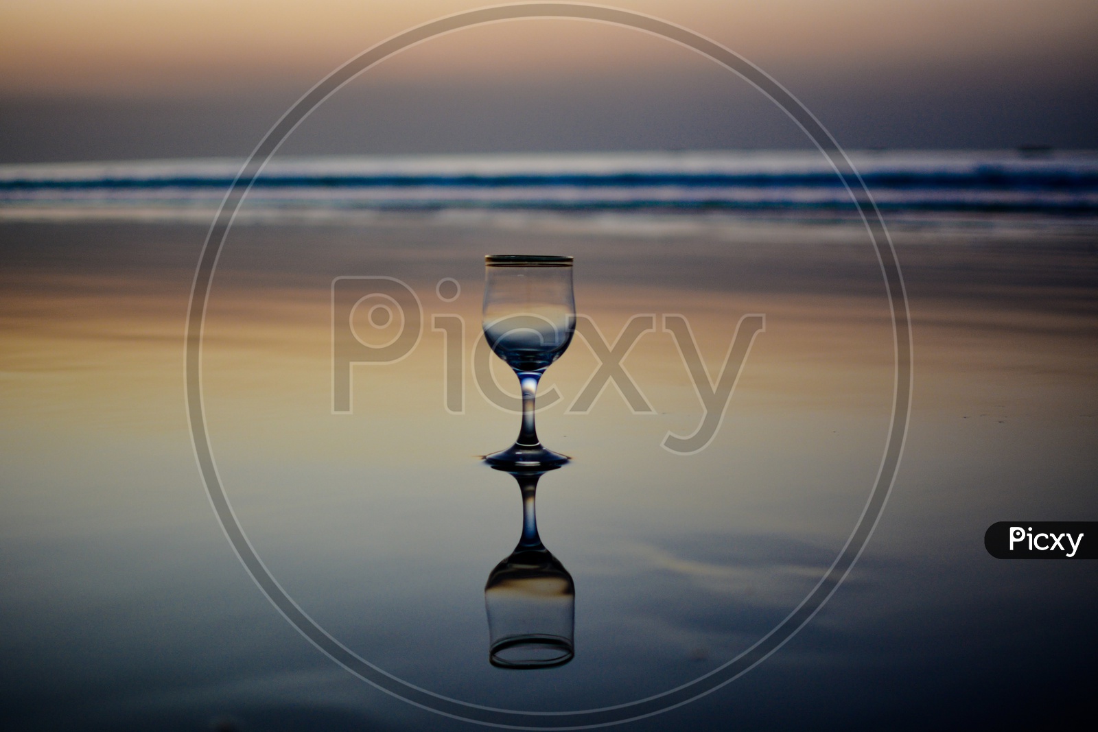 A Wine Glass and Its Reflection On the Beach Water Surface Over a Blue Hour Sky