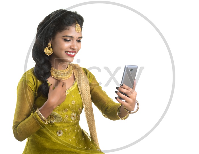Traditional Young Indian Girl Making Video Call On Her Smart Phone and With Smile Face And Showing Ornaments   On an Isolated White Background