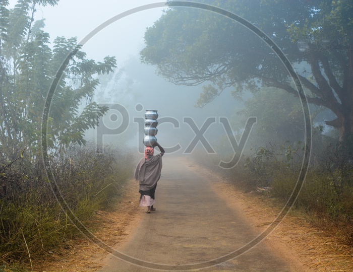 A Tribal Woman Carrying Water Vessels On Her Head