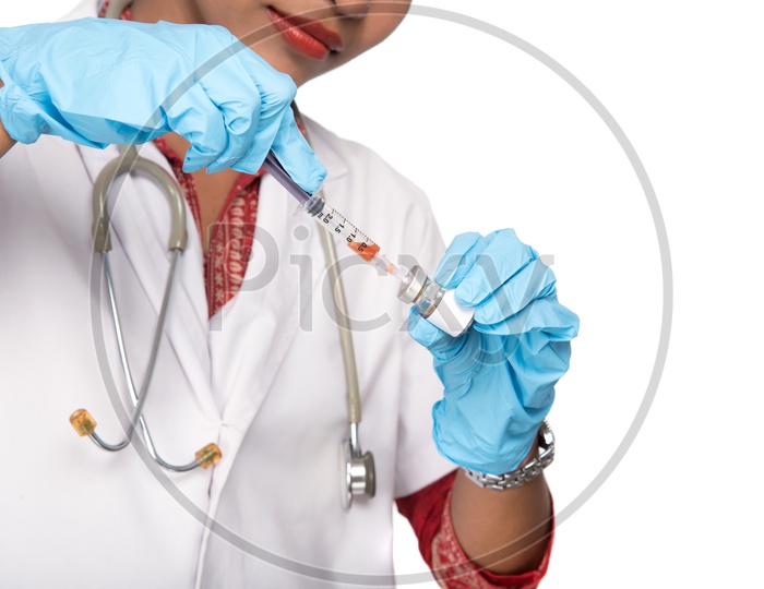 Young Lady Doctor Wearing Surgical Gloves  And Taking medicine Into Syringe   On an Isolated White Background
