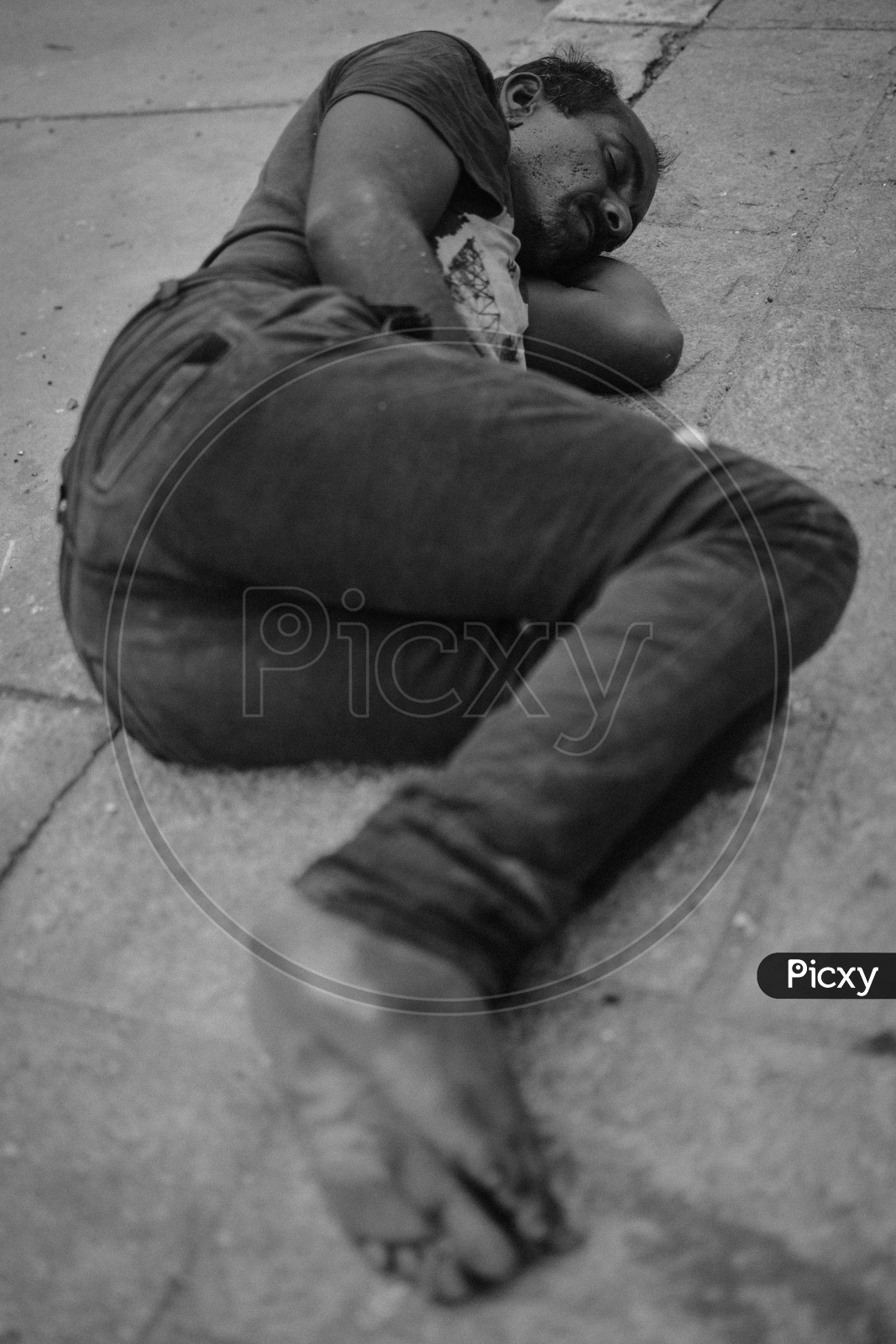 A Man Sleeping On Roadside Platform