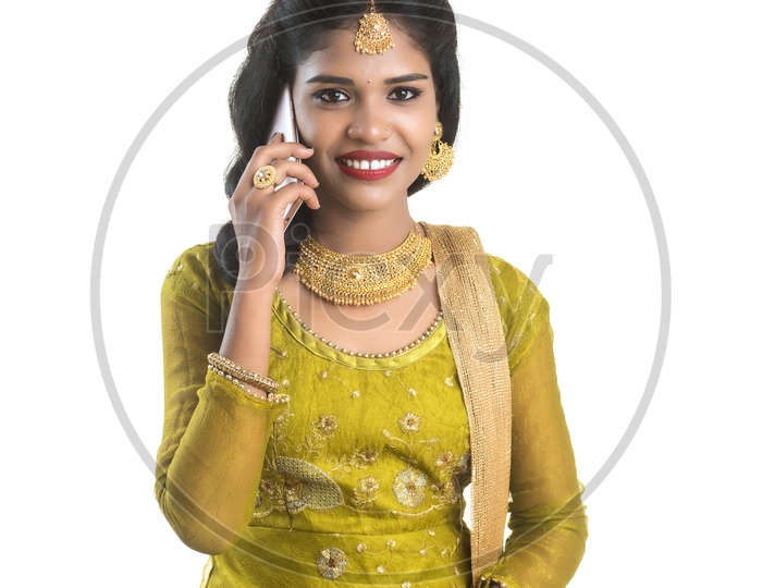 Young Traditional Indian Girl Speaking In Mobile phone Or Smart Phone With Smile On Her Face On an Isolated White Background