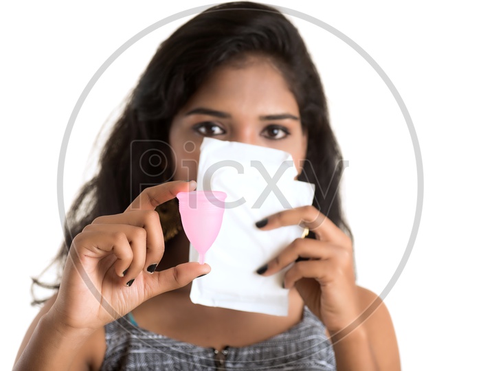 Indian woman holding a menstrual cup and sanitary napkins