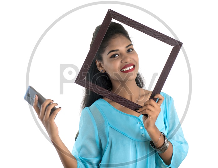 Pretty Young Indian Girl Taking Selfie Using Photo Fames in Her Smart Phone On an Isolated White Background