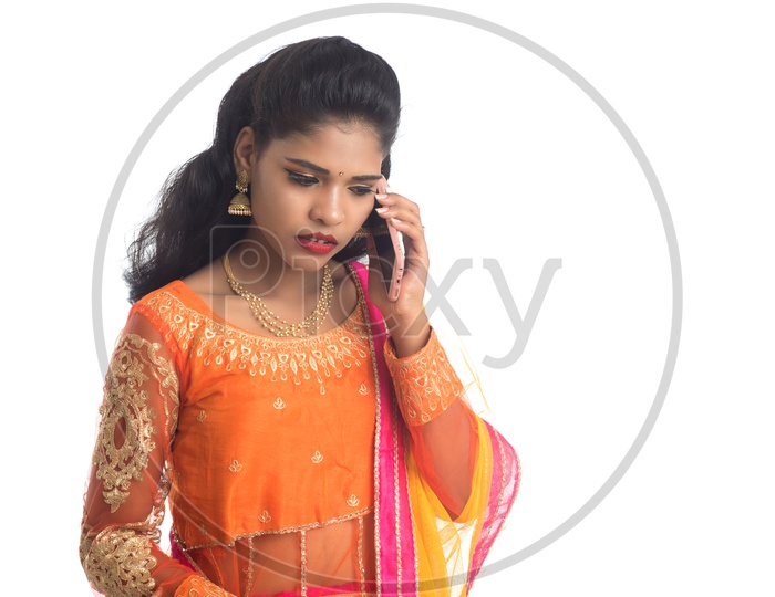 A Traditional Young Indian Woman Talking In Smart Phone And Posing On an Isolated White Background