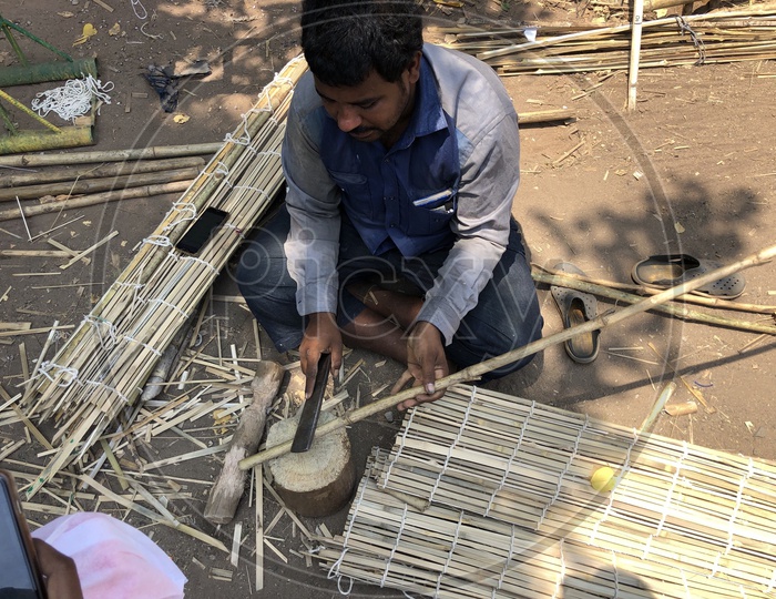 Indian man cutting the bamboo sticks
