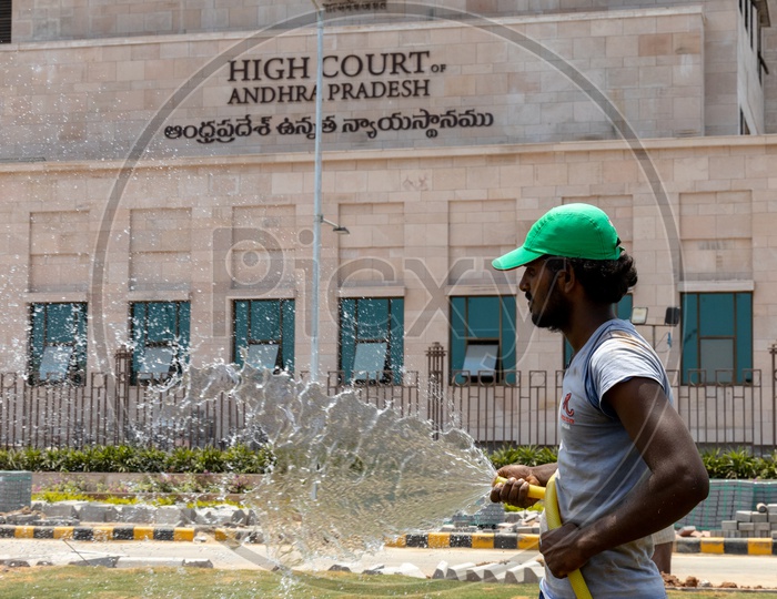 A Man watering the lawn in front of the High Court of Andhra Pradesh