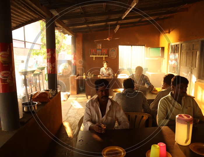 People Eating By Sitting in a Road Side Hotel or Eateries