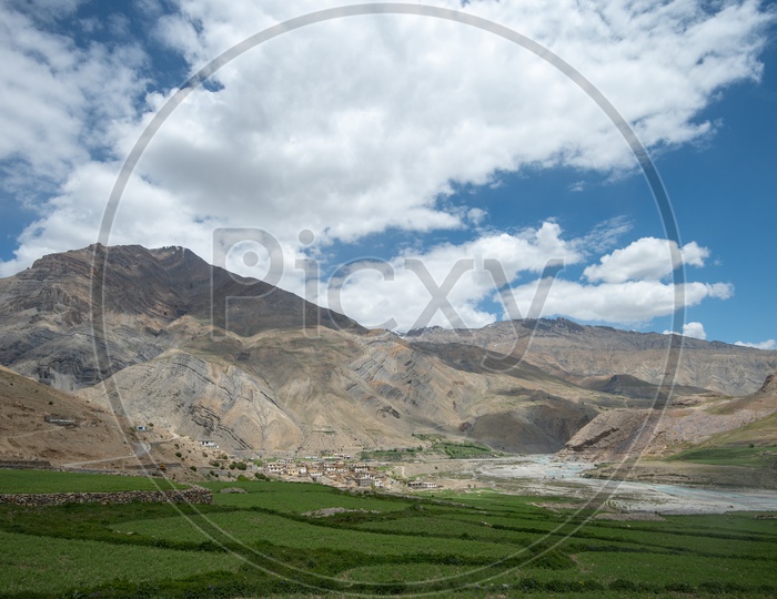 Houses and farm lands beside Spiti river with mountains in the background