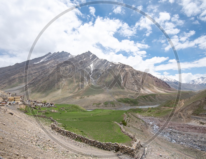 Agricultural farm lands and houses beside Spiti river with mountains in the background