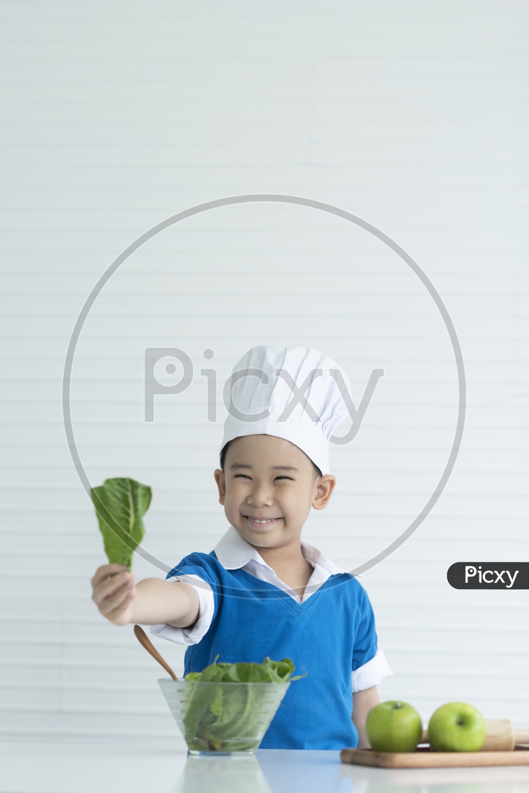 A Young Thai Boy Chef Showing Fresh Vegetables With a Smile Face