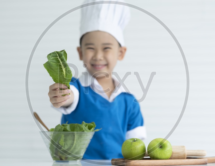 A Young Thai Boy Chef Showing Fresh Vegetables With a Smile Face