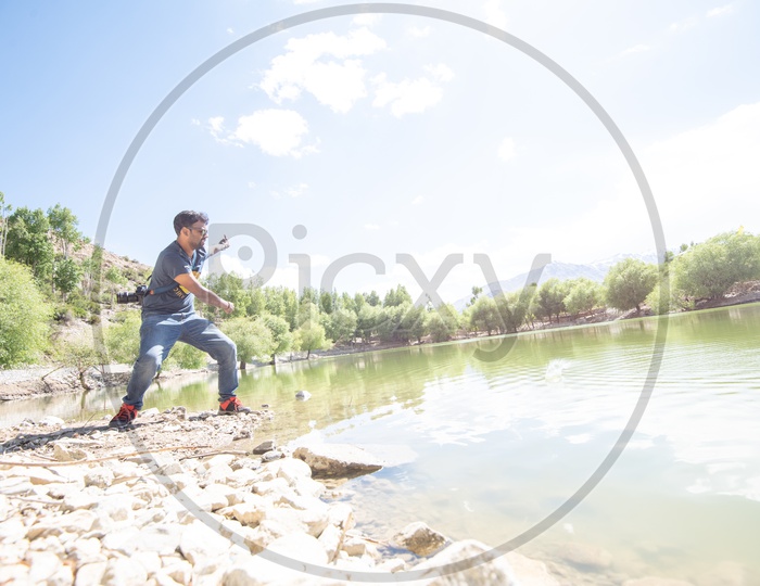 A Man Throwing Stones To Slide  Over Water Surface of a lake