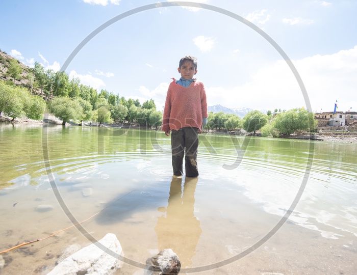 A Young Boy Standing at a Lake In villages of Leh