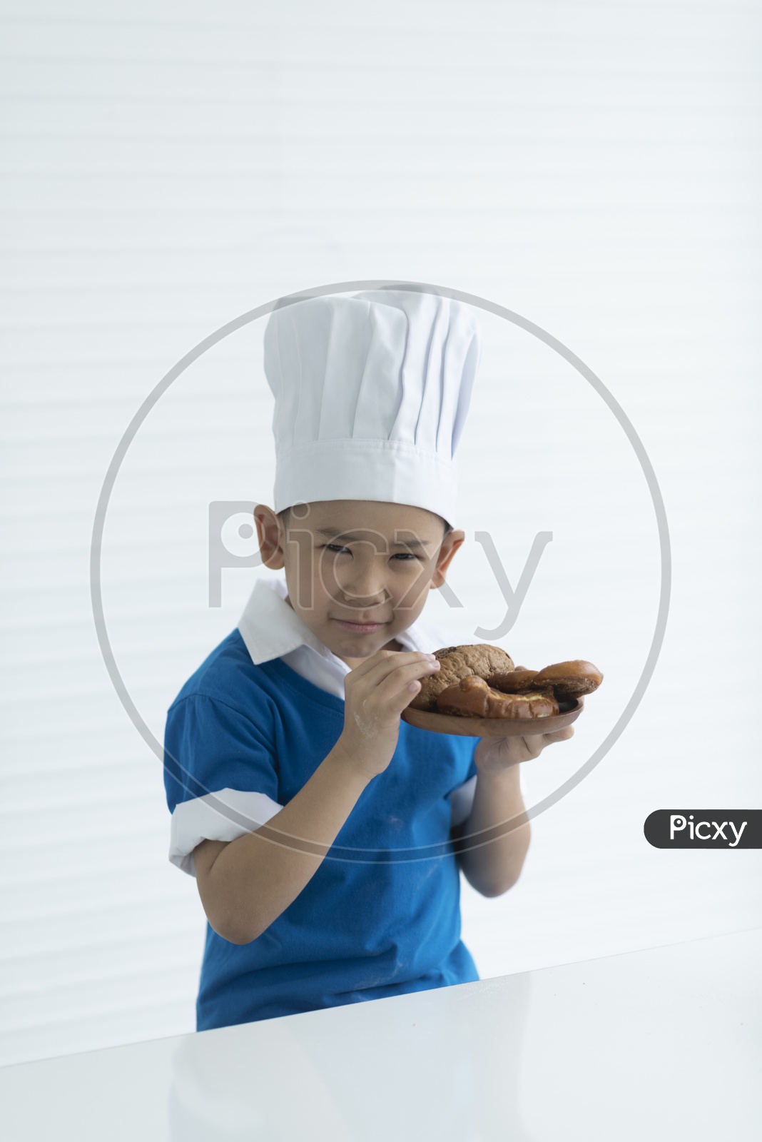 A Young Thai Boy Chef Smelling The Freshly Baked Bread in Kitchen
